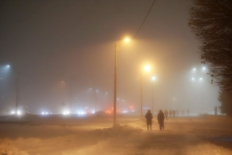 Фото заснеженной вечерней улицы. Тёплый свет фонарей сквозь густой туман